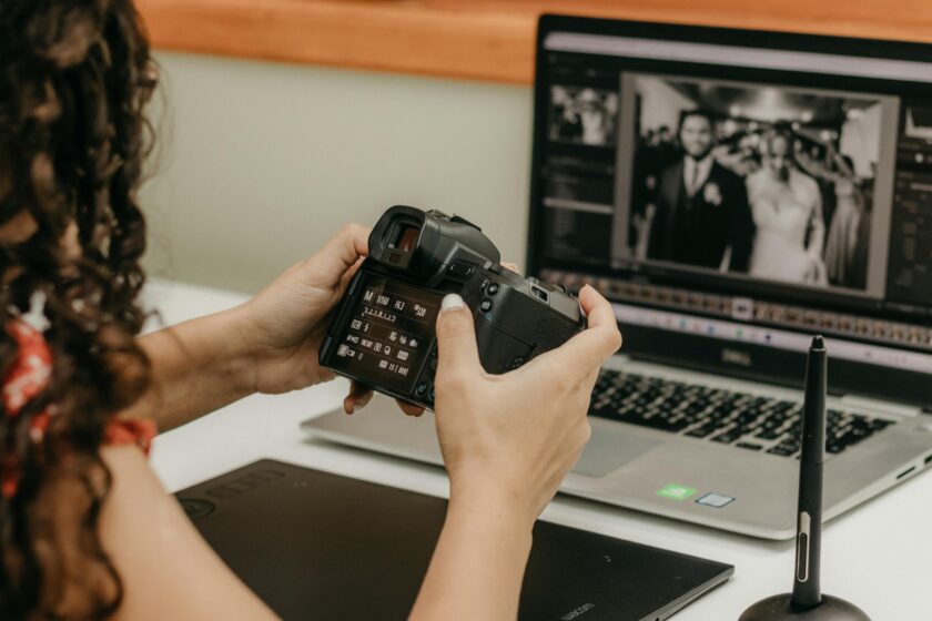 Photographer looking at Camera near Laptop